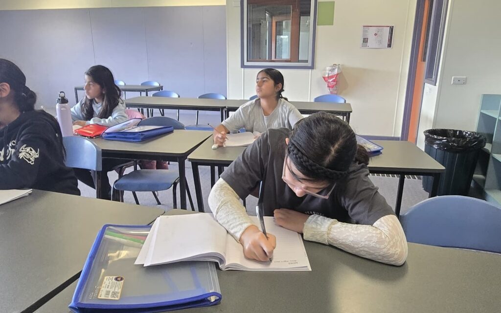 A NRICH Learning student writing in her workbook during a tutoring session
